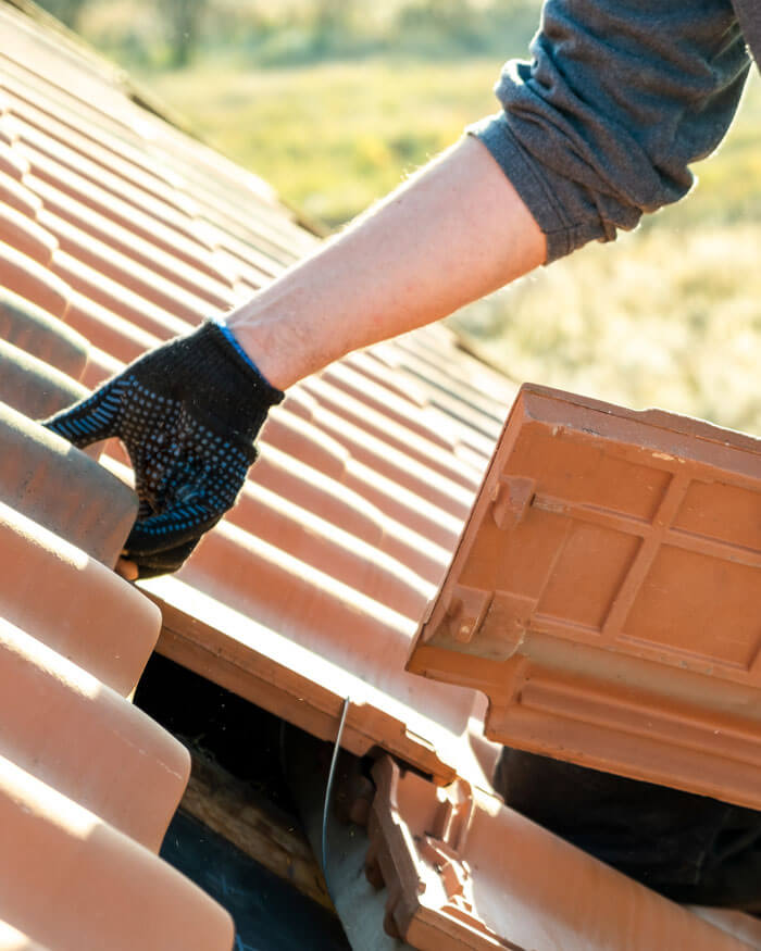 Closeup Of Worker Hands Installing Yellow Ceramic Roofing Tiles