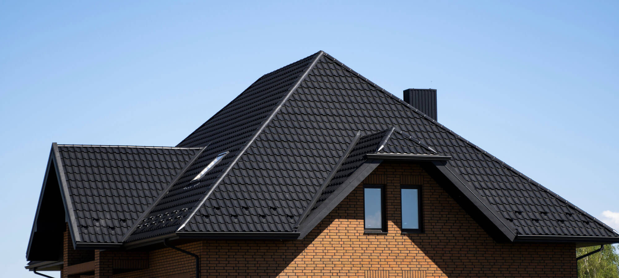Brown Corrugated Metal Profile Roof Installed On A Modern House With A Attic Windows. The Roof Of Corrugated Sheet. Roofing Of Metal Profile Wavy Shape. Modern Roof Made Of Metal. Metal Roofing.