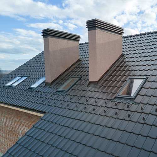 Closeup Of Attic Windows And Brick Chimneys On House Roof Top Covered With Ceramic Shingles. Tiled Covering Of Building